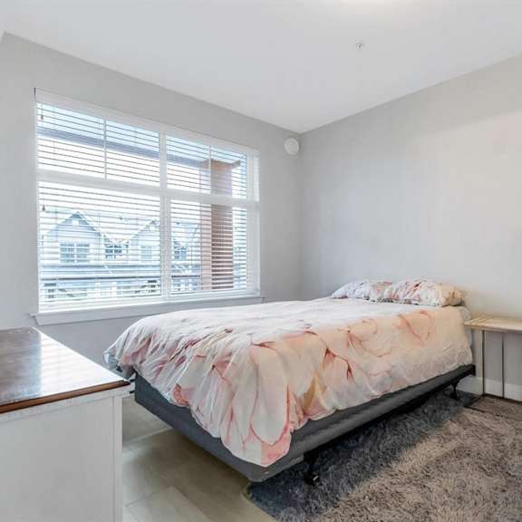 a bedroom with a bed, nightstand, and window with blinds.