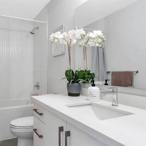 a white bathroom with a toilet, sink, and a shower curtain.