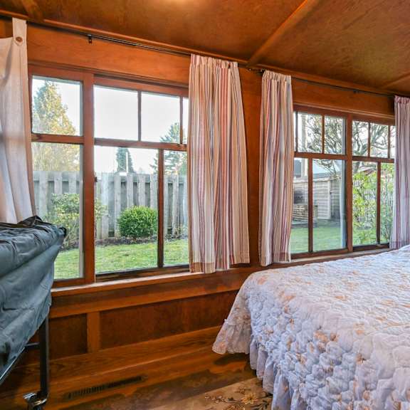 a bedroom with a large bed and a view of a fence and trees outside the window.