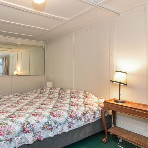 a bedroom with a bed, a lamp, and a mirror.