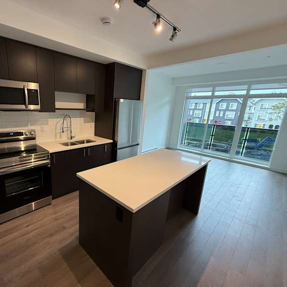 a modern kitchen with dark brown cabinets and a white island.