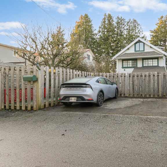 a white car is parked in front of a wooden fence.