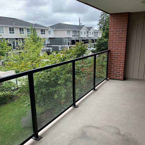 a balcony with a glass railing overlooking a residential area.