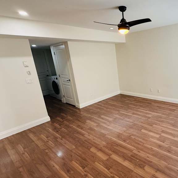 a room with a ceiling fan and wooden flooring.