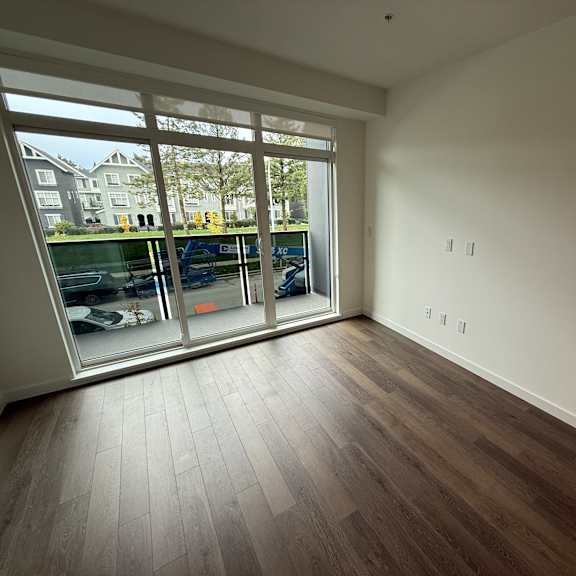 a room with a large window and wooden flooring.