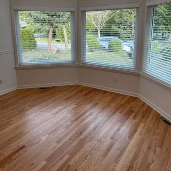 a room with wooden floors and windows overlooking a street.