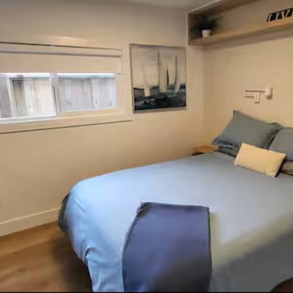 a bedroom with a bed, a window with blinds, and a wooden bench.