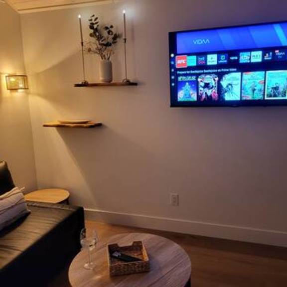 a living room with a black leather couch and a flat screen tv mounted on the wall.