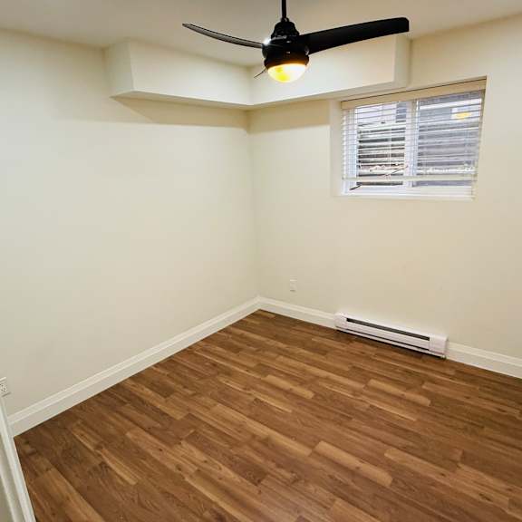 a room with a ceiling fan and a window with blinds.