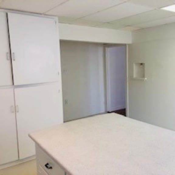 a white table in a room with white walls and a white cabinet.