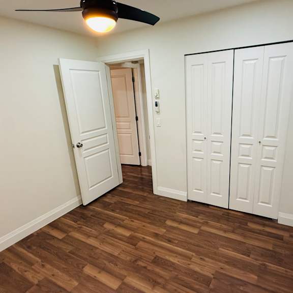a room with a ceiling fan and wooden flooring.