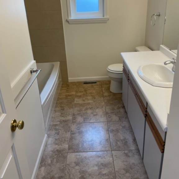 a bathroom with a toilet, sink, and window.