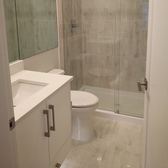 a white toilet with a white sink and a glass shower stall.