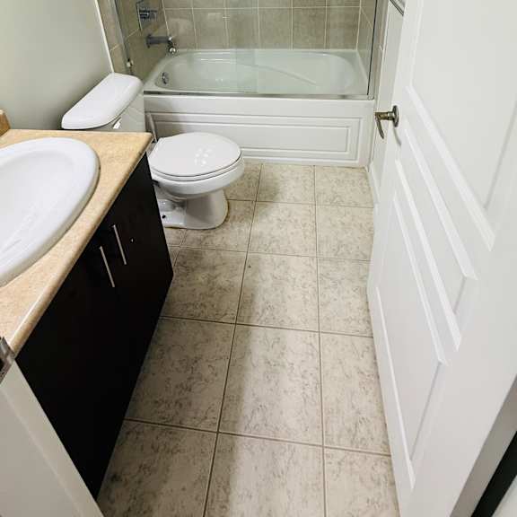 a bathroom with a toilet, sink, and shower.