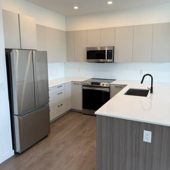 a modern kitchen with a stainless steel refrigerator, microwave, and dishwasher.