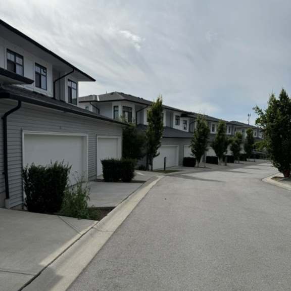 a residential street with houses on both sides and a cloudy sky.
