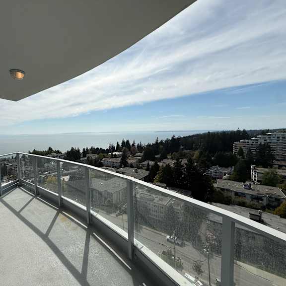 a balcony with a glass railing overlooking a cityscape.