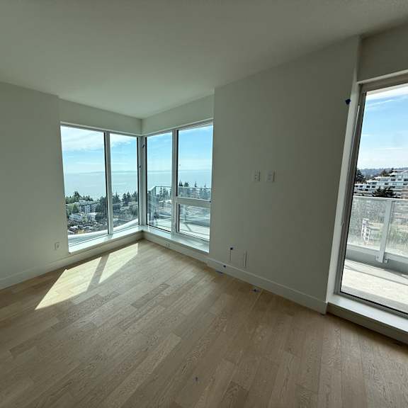 a room with wooden flooring and large windows overlooking a cityscape.