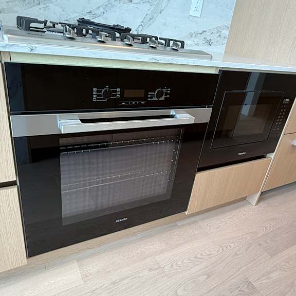 a modern kitchen with a black oven and wooden cabinets.