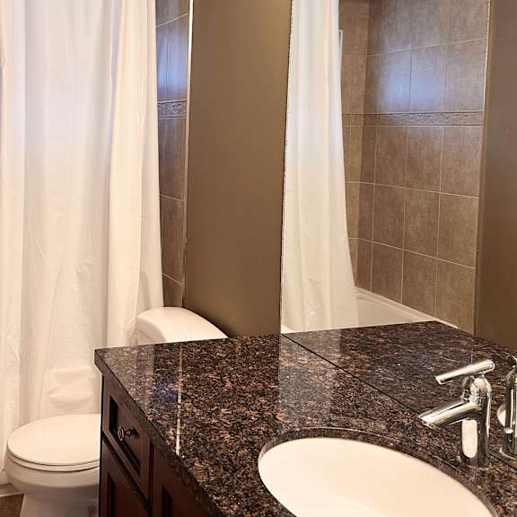 a bathroom with a white toilet, a bathtub, a sink, and a shower curtain.