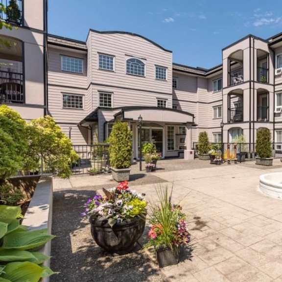 a courtyard with a fountain and potted plants in front of a building.