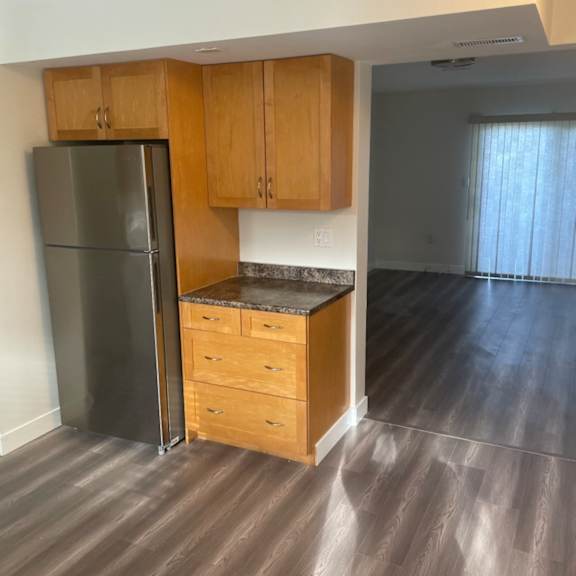 a kitchen with a refrigerator, cabinets, and a countertop.