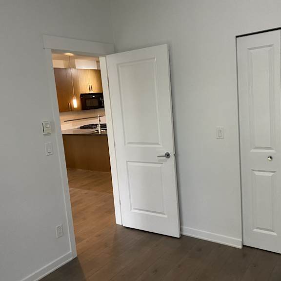 a white door is open to a kitchen.