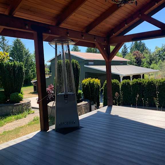 a patio with a fan and a house in the background.