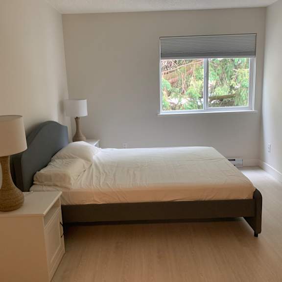 a bedroom with a bed, nightstand, and lamp.