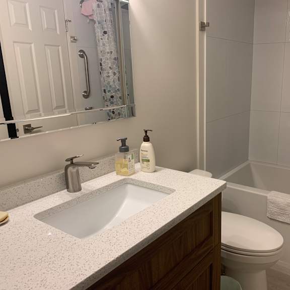 a white sink in a bathroom with a toilet and a mirror.