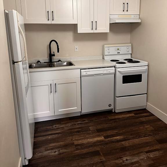 a white fridge and freezer in a kitchen with wooden walls.