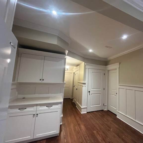 a room with white cabinets and wood floors.