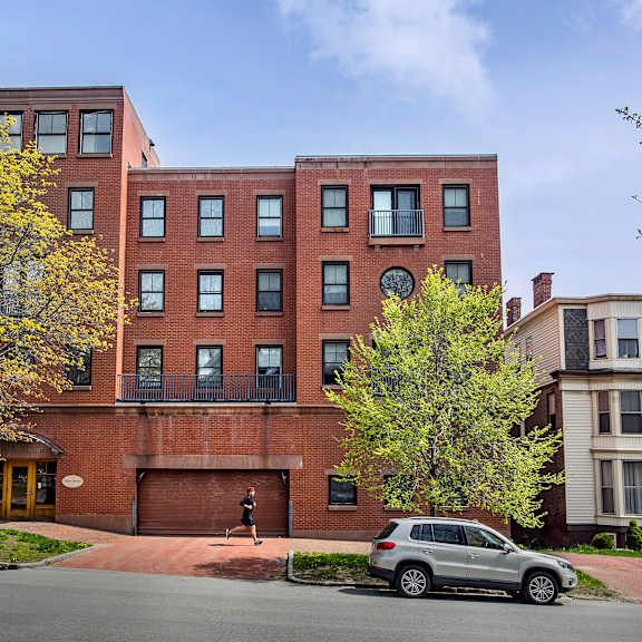 a grey car is parked in front of a red brick building.