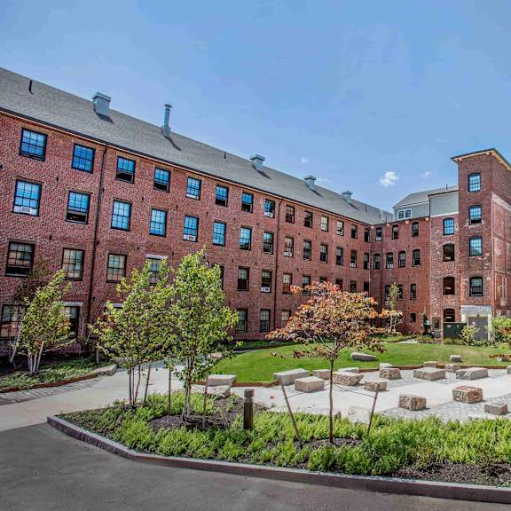 a courtyard with a garden in front of a red brick building.