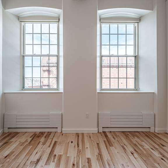 a room with two windows and wooden floors.