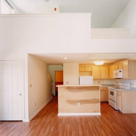 a kitchen with wooden floors and white walls.