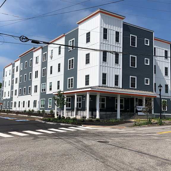 a street view of a multi-story building with a crosswalk in front.