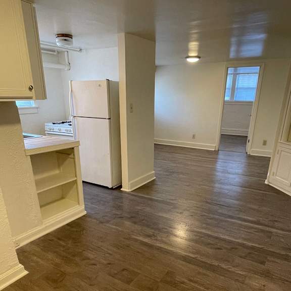 a kitchen with a white fridge and wooden floors.