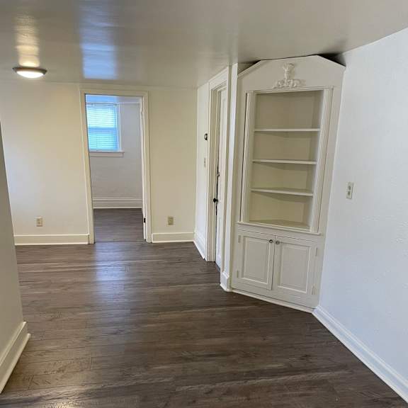a long hallway with wood floors and white walls.