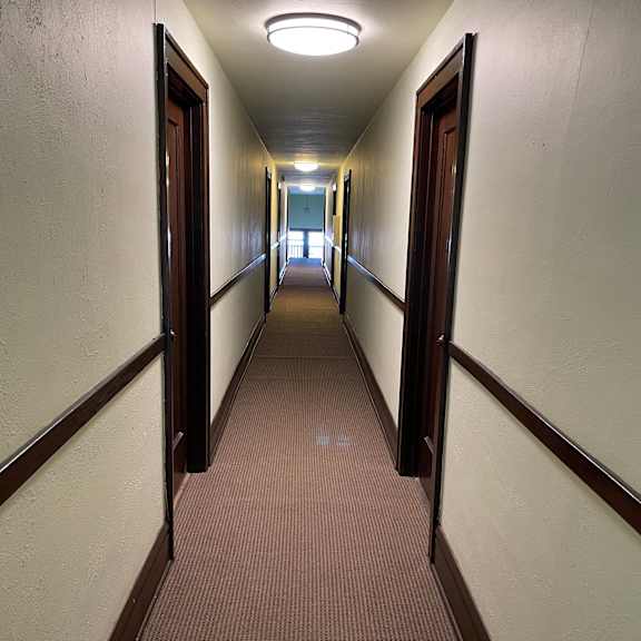 a long hallway with brown carpeting and white walls.