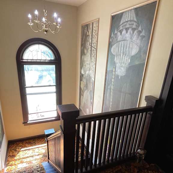 a staircase with a chandelier and a picture on the wall.