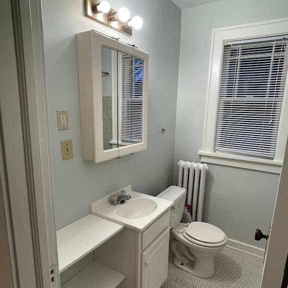a white bathroom with a toilet, sink, and mirror.