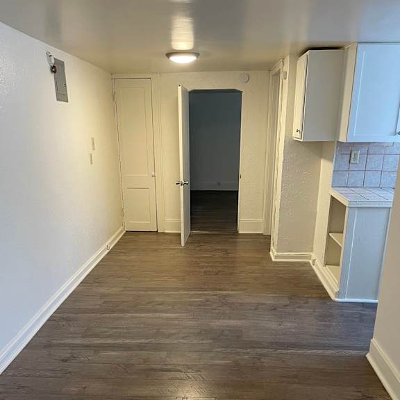 a long hallway with wood floors and white walls.
