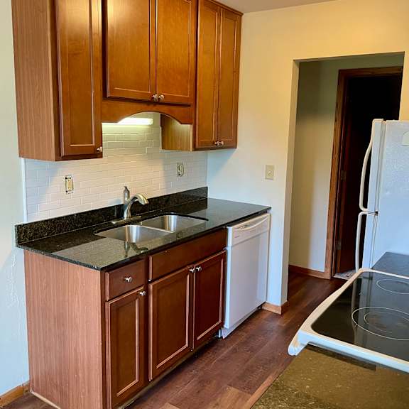 a kitchen with wooden cabinets and a black counter top.