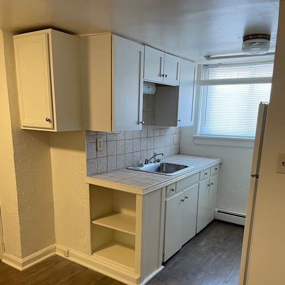 a kitchen with white cabinets and a wooden floor.