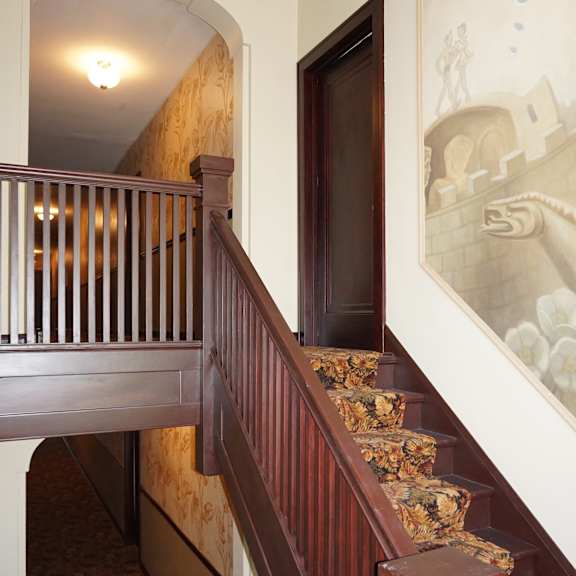 a staircase with a wooden handrail and a patterned carpet.