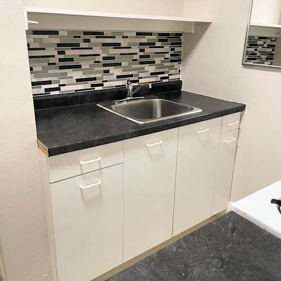 upgraded kitchen with new countertops, sink, faucet and decorative mosaic tile backshplash.