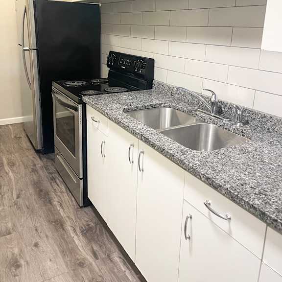 updated kitchen with granite countertops, stainless steel appliances and ceramic tiled backsplash.