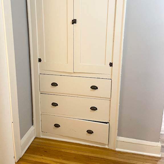 a white wardrobe with three drawers is open.