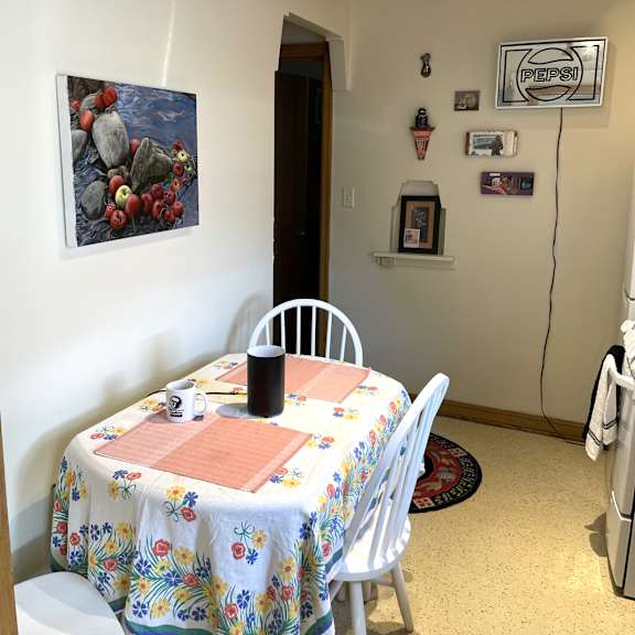 a dining room with a floral tablecloth and a painting of rocks on the wall.
